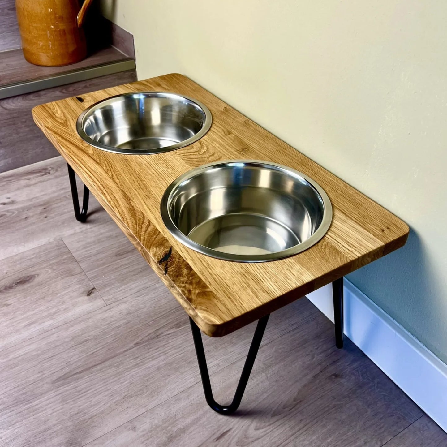 Futterstation für Hunde mit Edelstahlnäpfen und filigranen Fußgestellen kombiniert mit einer Eichenholzbohle mit geraden Kanten und geölter Oberfläche minimalistisches Design