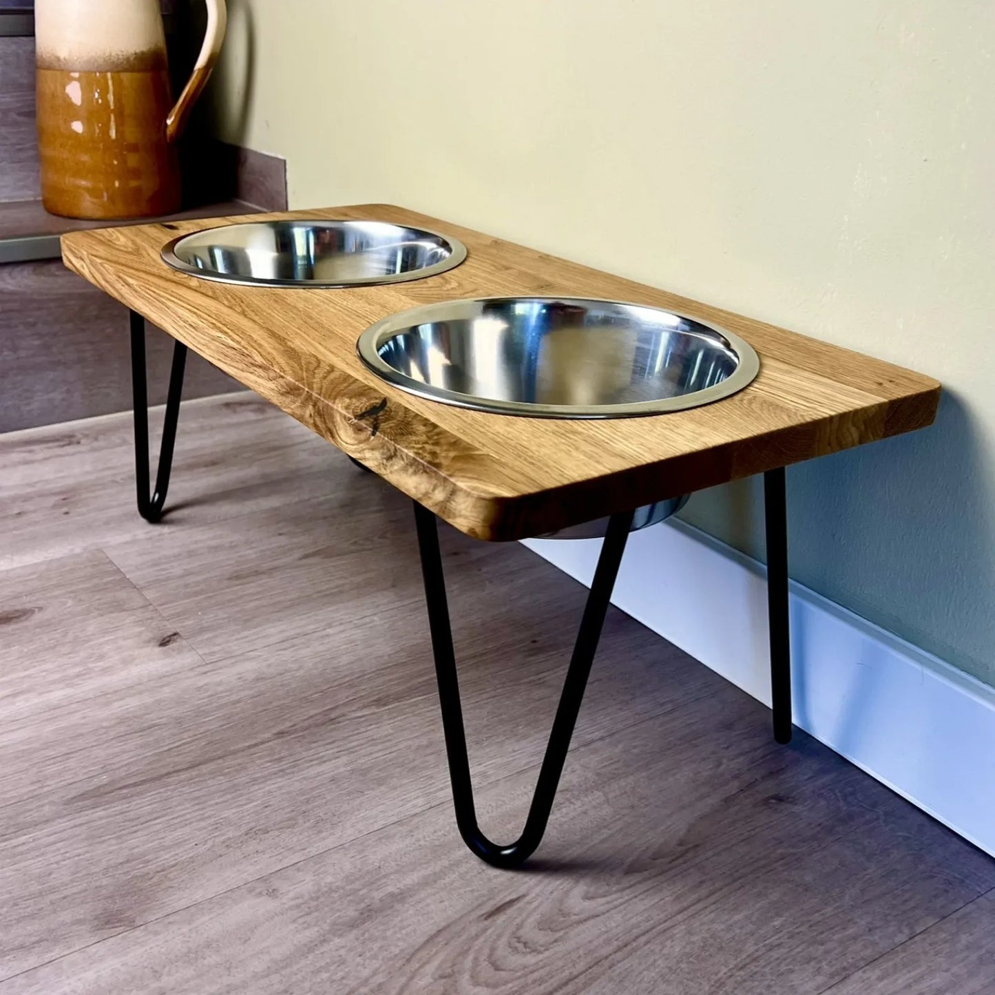 Hundefutterstation erhöht mit Edelstahlnäpfen und filigranen Fußgestellen kombiniert mit einer Eichenholzbohle mit geraden Kanten und geölter Oberfläche minimalistisches Design