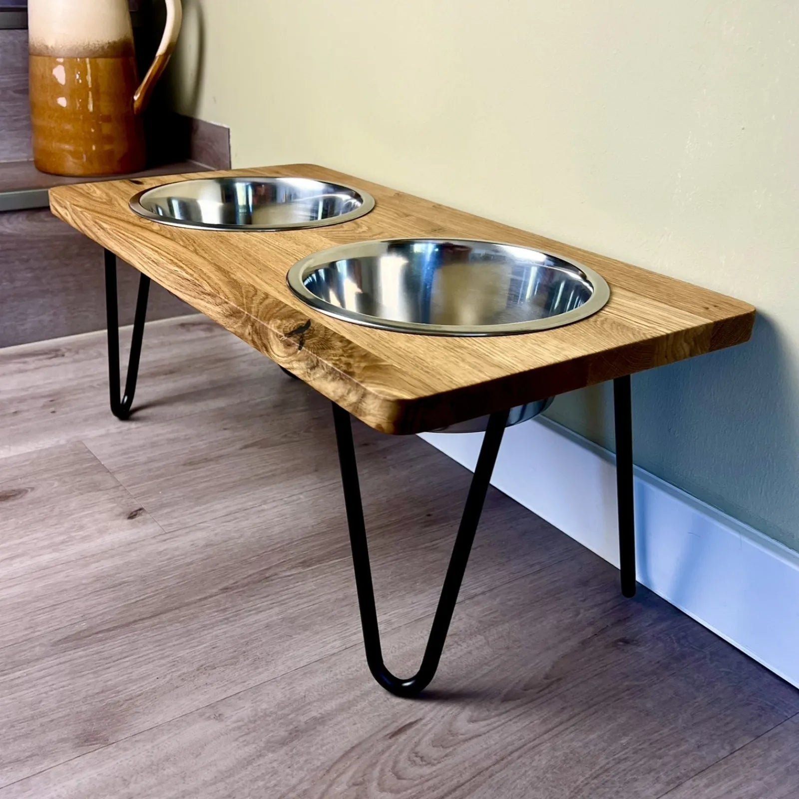 Hundefutterstation erhöht mit Edelstahlnäpfen und filigranen Fußgestellen kombiniert mit einer Eichenholzbohle mit geraden Kanten und geölter Oberfläche minimalistisches Design