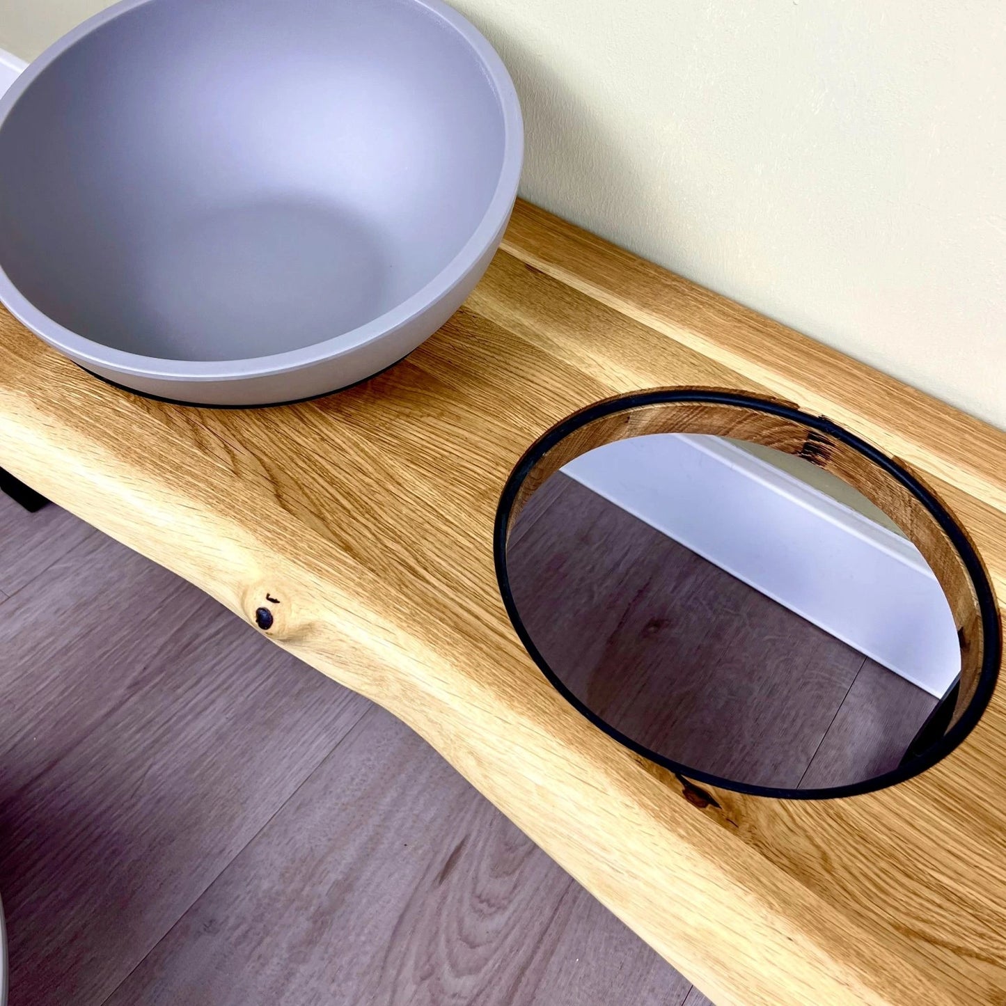 Detailansicht der Napfhalterung der Design Futterstation für Hunde mit natürlicher Eichenholzbohle und geradlinigen Fußgestellen mit natürlich herausgearbeiteter Baumkante und Betonoptik Näpfen aus Melamin
